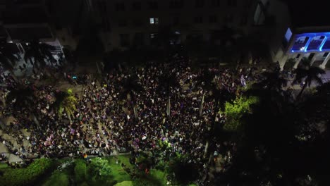 Night-aerial-view-of-Women's-Day-march-in-Santa-Cruz-square,-Bolivia