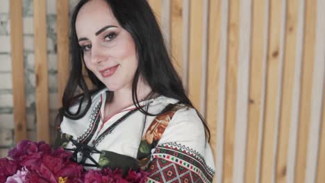 portrait-features-a-beautiful-young-woman-holding-a-bouquet-of-beautiful-flowers,-dressed-in-an-embroidered-authentic-Ukrainian-shirt
