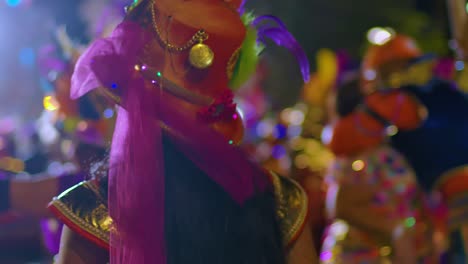 Beautiful-light-skin-woman-smiles-blowing-kiss-as-she-dances-away-during-Carnival-parade-at-night