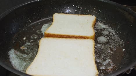 Two-thick-slices-of-white-bread-are-set-into-hot-buttered-pan-on-stove