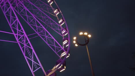 Purple-ferris-wheel-medium-shot,-ground-level-side-shot-in-night-time,-street-lamp