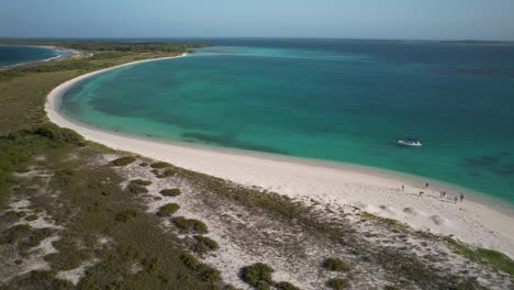 A-serene-beach-on-los-roques-archipelago-with-crystal-waters-and-sparse-visitors,-aerial-view