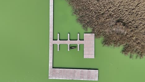 Descending-shot-of-fishing-platform-on-stilts-by-a-lake-in-northern-Greece-|-Top-down-shot-of-a-fishing-platform-in-murky-green-water