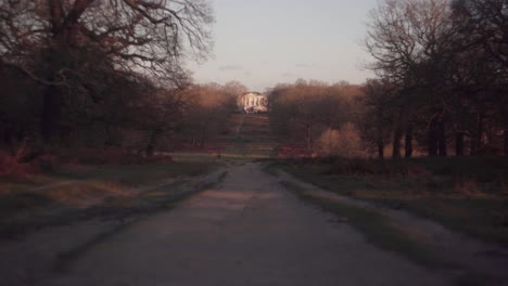 A-pathway-leading-to-a-large-house-on-a-bright-cold-winter-afternoon-in-Richmond-Park,-United-Kingdom