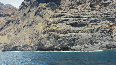 Rocky-cliff-coastline-of-Tenerife,-view-from-moving-boat