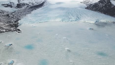 Vista-Aérea-Del-Lago-Congelado-Junto-Al-Glaciar-De-Montaña-En-Vatnajokull,-Islandia