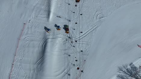 Top-down-tracking-shot-flying-down-mountain-following-cable-car-chair-lift