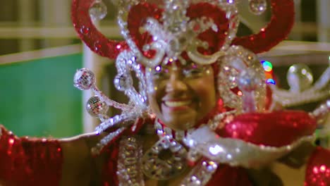 Vibrant-black-woman-shimmy-dancing-with-joy-in-red-and-white-sparkling-shoulder-costume-and-headdress