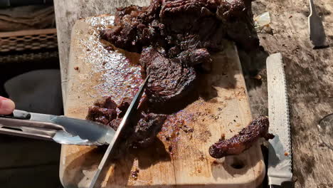 Carne-Roja-Cortada-Sobre-Una-Tabla-De-Cortar-De-Madera-Durante-Una-Barbacoa-Al-Aire-Libre