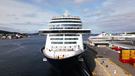 Großes-Kreuzfahrtschiff-Liegt-Im-Hafen-Und-Leute-Gehen-Weg,-Bergen,-Norwegen,-Europa,-Drohne