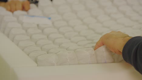 Hand-placing-layers-on-a-boxspring-bed-in-a-factory,-close-up