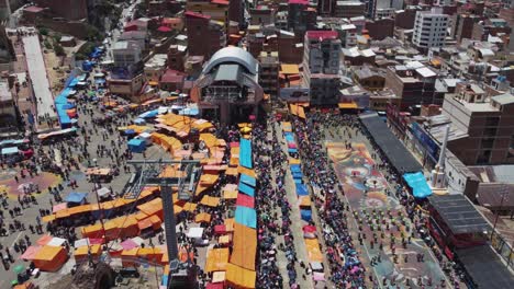 Aerial-follows-cable-cars-to-crowded-public-square-carnival,-Oruro-BOL