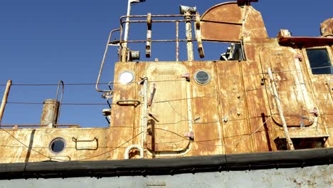 Rostiges-Boot-An-Einem-Strand-Mit-Blauem-Himmel-Und-Klarem-Wetter-Im-Hintergrund,-Gelb,-Mit-Moos-Bewachsen-Und-Unbrauchbar