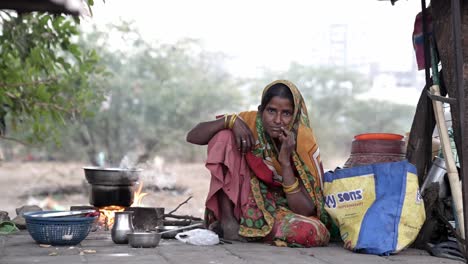 Cinematic-Shot-Woman-from-Street-is-making-dinner-for-his-family-on-the-sidewalk-and-is-looking-at-the-camera