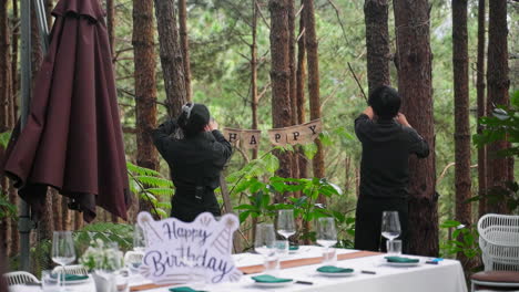 Gente-Preparando-Una-Pancarta-De-Fiesta-Para-Una-Alegre-Celebración-En-El-Jardín