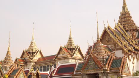 looking-up-at-towering-detailed-golden-pagoda-spires-in-a-buddhist-temple-complex-in-the-Rattanakosin-old-town-of-Bangkok,-Thailand