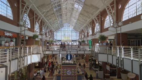 Plano-Panorámico-Estático-Dentro-Del-Centro-Comercial-En-Sudáfrica-Ciudad-Del-Cabo-Arquitectura-Moderna-De-Tiendas-Blancas-De-Madera-Y-Gente-Comprando-Dentro-Del-área-Comercial