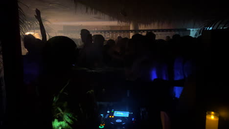 A-dj-performing-at-Nido-beach-club-in-Estepona-Spain,-fun-nightlife-in-Marbella,-best-party-vibes-with-people-dancing,-4K-shot