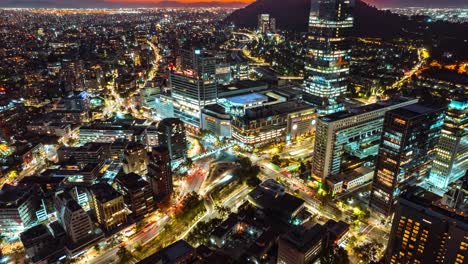 Vista-Aérea-Nocturna-Del-Bullicioso-Distrito-De-Las-Condes,-Mostrando-Las-Luces-De-La-Ciudad-Y-La-Actividad-Urbana,-Timelapse