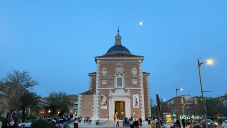 Vemos-La-Parroquia-De-Nuestra-Señora-De-Las-Angustias-De-Frente-Con-La-Luna-Poniéndose,-Y-Gente-A-Su-Alrededor.