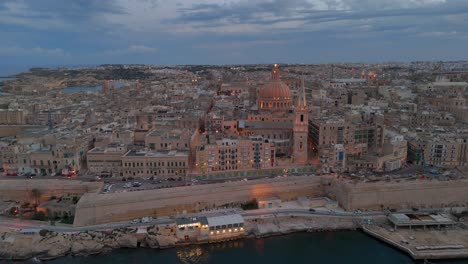 An-aerial-view-of-the-ancient-town-of-Valletta-in-Malta-at-dusk,-as-it-begins-to-light-up-for-the-night