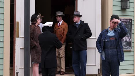 Reenactment-of-1940s-United-states-men-and-women-gather-in-doorway-of-hotel-talking-after-World-War-II-at-the-Ohio-Village,-at-the-Ohio-History-Connection