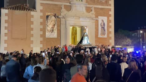 Filmación-De-La-Salida-De-La-Imagen-De-La-Virgen-De-La-Parroquia-Por-La-Puerta-Principal-Sostenida-Por-Los-Feligreses,-Hay-Una-Gran-Multitud-De-Fieles-En-La-Procesión-Vemos-Los-Carteles-Del-Evento