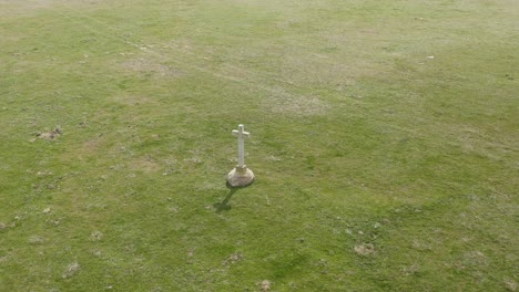 Imágenes-De-Alta-Calidad-Con-Un-Dron-Orbitando-Sobre-Una-Cruz-De-Piedra-Blanca-Con-Un-Pedestal-De-Granito-En-Bruto-Y-Proyectando-La-Sombra-De-La-Cruz-En-El-Suelo-Ubicado-En-Un-Prado-Verde-En-Ávila,-España