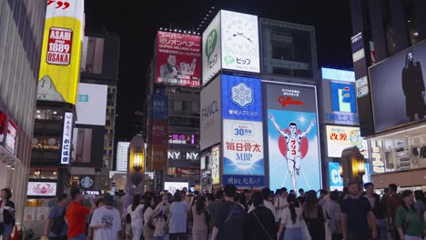 Nachtzeit-Zeitlupenaufnahme-Von-Vorbeigehenden-Menschenmassen-Und-Beleuchteten-Schildern-An-Der-Ebisubashi-Brücke-Auf-Dem-Dotonbori-Kanal-In-Osaka,-Japan