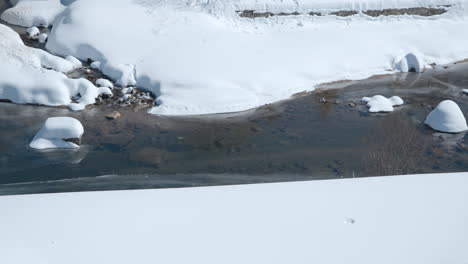 Panning-Along-the-Snow-capped-stream-or-sreek-in-winter