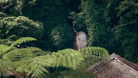 Movimiento-Ambiental-De-Las-Aguas-De-La-Cascada-Pulangbato-Entre-El-Exuberante-Follaje-De-La-Jungla-Enmarcado-Por-Helechos-Y-Techos-De-Bungalows-Nativos