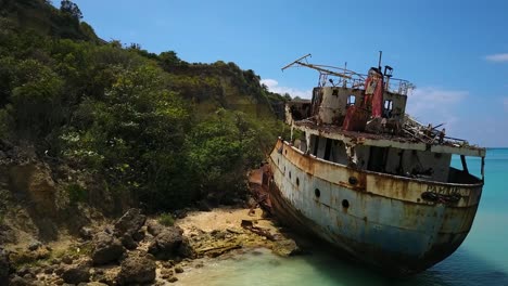 Push-in-and-Rotate-Aerial-Drone-shot-of-Shipwreck-in-Anguilla-with-clear-blue-skies-on-the-Caribbean-shoreline