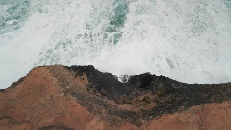 Top-view-of-ocean-water-hitting-the-coastline-of-Cape-Bridgewater,-Australia