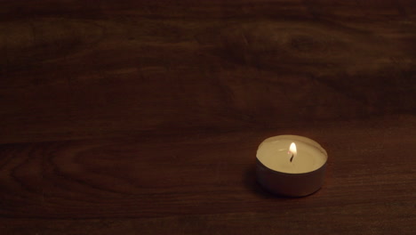 Copy-space-wooden-table-top-with-one-tea-light-candle-in-lower-corner
