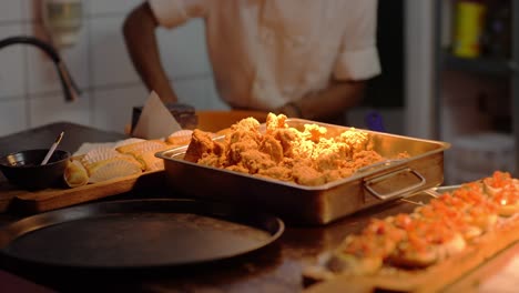 Deep-fried-chicken-on-display,-ready-for-serving,-chef-busy-in-background