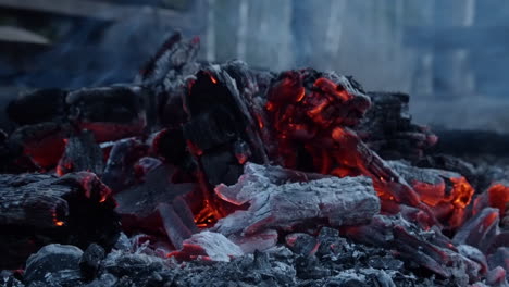 Close-up:-Stick-used-to-arrange-hot-orange-fire-coal-embers-outside