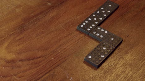 Schwarze-Dominosteine-Mit-Weißen-Punkten-Auf-Einem-Holztisch-Platziert