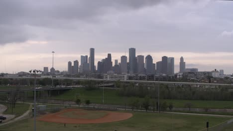 Ascending-drone-shot-of-downtown-Houston,-Texas-from-neighborhood-park