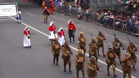 Infanterie-Der-Australischen-Armee,-Soldaten-Mit-Scharfschützengewehr-Marschieren-Die-Straße-Entlang,-Gefolgt-Von-Frauen-In-Krankenschwesteruniformen-Aus-Dem-Ersten-Weltkrieg,-Die-An-Der-Jährlichen-Traditionellen-Anzac-Day-Parade-Teilnehmen