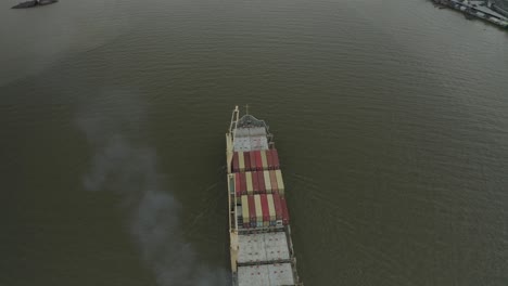 Cargo-ship-top-down-drone-view,-city-in-background-reveal