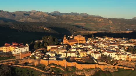 Aerial-closeup-historic-Islamic-city-walls-in-Spain-Ronda-architecture-moorish-houses-in-Travel-mediterranean-destination,-green-mountains-skyline-background