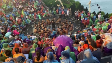 Una-Gran-Multitud-De-Turistas-Observa-Un-Espectáculo-De-Danza-Kecak-Vistiendo-Impermeables-En-El-Templo-De-Uluwatu,-Bali,-Indonesia,-A-Pesar-De-Una-Tormenta