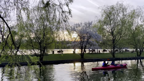 Park-Mit-See-Und-Menschen,-Die-Im-Boot-Entspannen