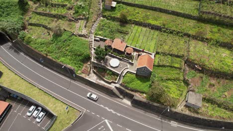 Seixal-terraced-hillside-rising-aerial-view-looking-down-over-João-Delgado-road-tunnel-entrance-in-Madeira