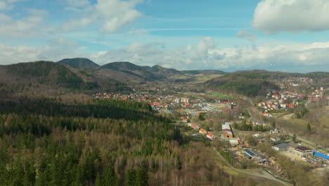 Aerial-approaching-shot-of-small-polish-town-in-scenic-mountain-landscape-at-sunny-day