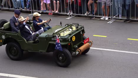 Senior-Veteran-Reiten-Auf-Dem-Militär-Jeep,-Fahren-Die-Straße-Hinunter,-Die-Teilnahme-An-Der-Jährlichen-Anzac-Day-Parade,-Winken-Auf-Die-Jubelnden-Massen-Der-Öffentlichkeit