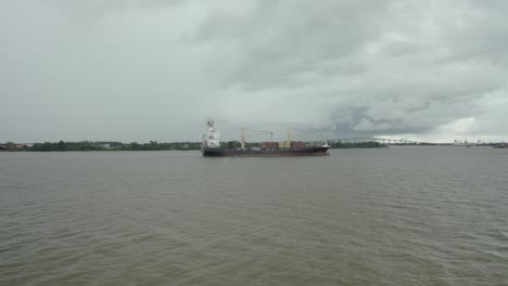 Buque-De-Carga-Navegando-En-El-Río-Surinam-Hacia-El-Puerto,-Vista-De-Drones-Ascendiendo-Hacia-El-Barco