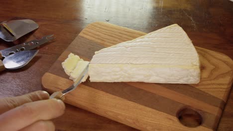 Weichkäse-Brie-Wird-Mit-Käsemesser-Auf-Holzschneidebrett-Geschnitten