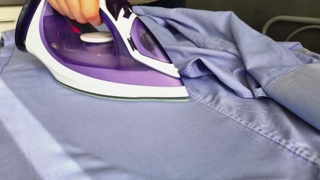 Close-up-of-an-iron-being-ironed,-purple-and-white