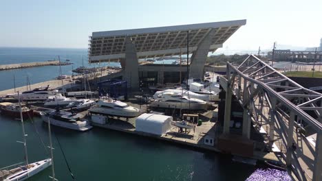 Toma-Aérea-Del-Parque-Del-Foro-De-Barcelona-Con-La-Costa-Al-Fondo-Y-Un-Espectacular-Paisaje-De-La-Ciudad-De-Barcelona-En-Un-Día-Soleado